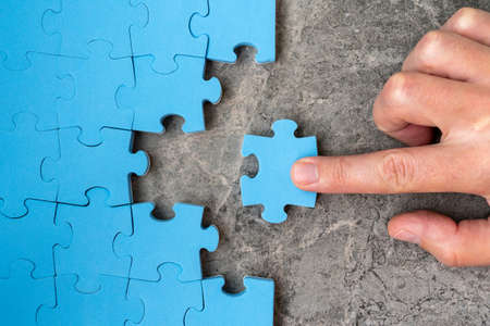Concept of business.Hand holding piece of jigsaw puzzle and insert into the missing hole