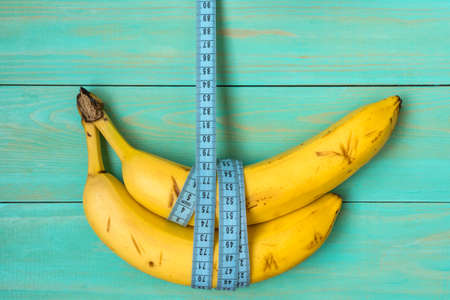 Bananas hanging on a measuring tape.Healthy eating or dieting concept