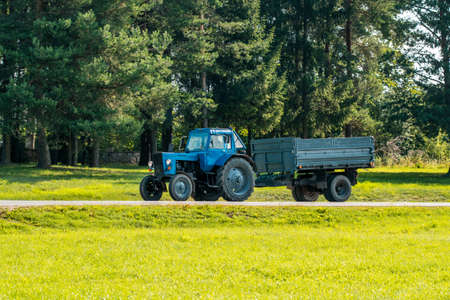 Tractor with a trailer goes on country road