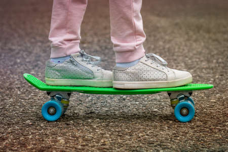 Closeup of skateboarder legs. Girl ride skateboard on a city street.
