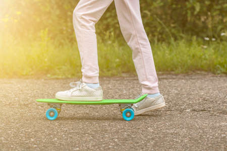 Close-up of skateboarder legs. Girl ride skateboard on a sunny day
