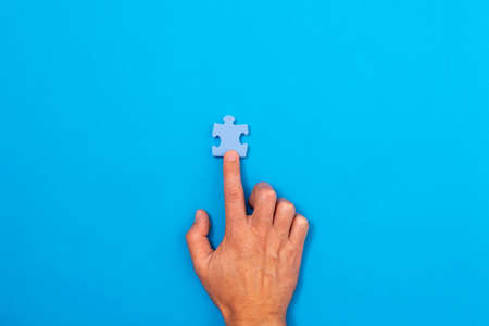 Concept of business. Hand pointing at pieces of puzzle ower a blue backgroundの写真素材