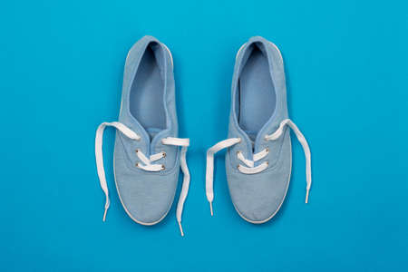 Flat lay of soft blue color canvas shoes on blue backgroundの写真素材