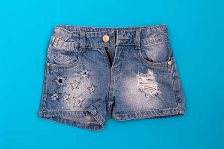 Ripped stylish jeans shorts on a blue backgroundの写真素材