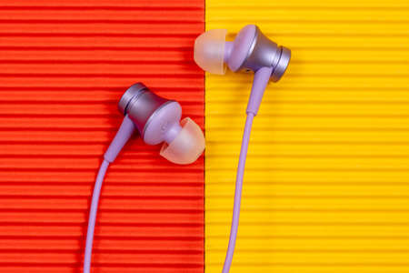 Purple audio earphones on the colorful paper background