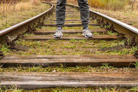 Man walking along railway. Legs of traveler on rail tracks. 