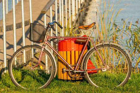 Old bicycle standing beside bridge of small lakeの写真素材