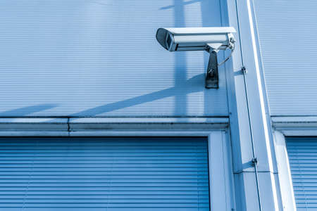 CCTV camera on the wall of industrial building. Blue toned image.の写真素材