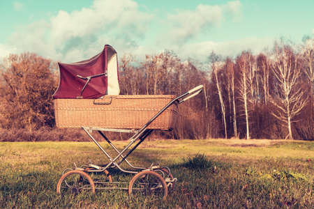 Retro style stroller baby carriage outdoors with autumn landscapeの写真素材