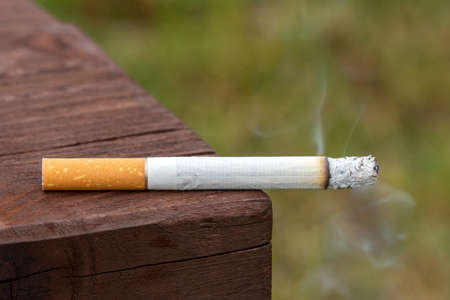 Close up of a cigarette on the bench in public placeの写真素材
