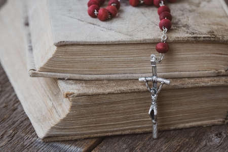 Catholic rosary with a cross lie on several ancient booksの写真素材