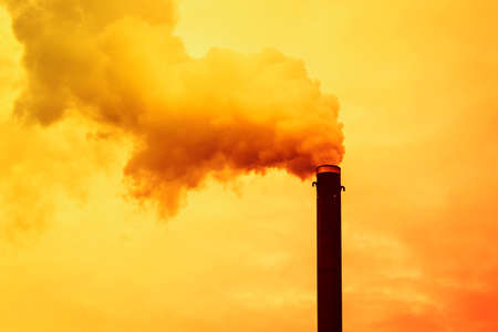 Emission to atmosphere from industrial pipe. Smoking pipe on sunset.