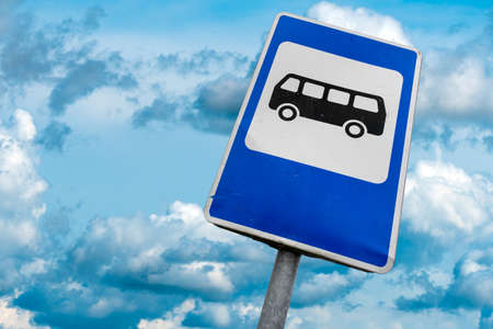 Bus stop sign in a front of cloudy skyの写真素材