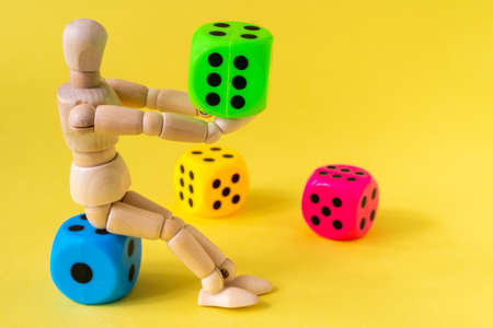 Wooden mannequin with game dice on the yellow backgroundの写真素材