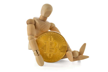 Wooden man holding Bitcoin while sitting on white backgroundの写真素材