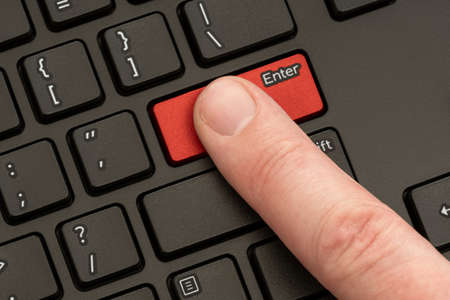Finger pressing the ENTER button of computer keyboard