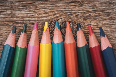 Colored pencil crayons on the wooden background, close-up view
