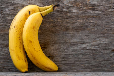 Pair of fresh bananas on wooden shelf. Copy space.の写真素材