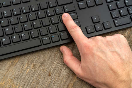 Hand typing on the remote wireless computer keyboard in an office at a workplaceの写真素材