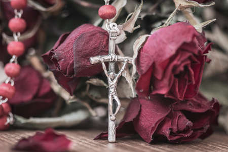 Catholic rosary and dry roses, close-up view. Faith and spirituality concept.の写真素材