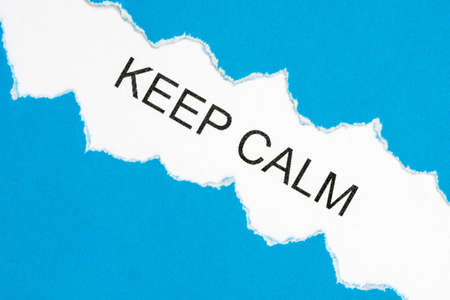 Top view of blue torn paper and the text KEEP CALM on a white background. Inspiration, motivation and business concept.の写真素材