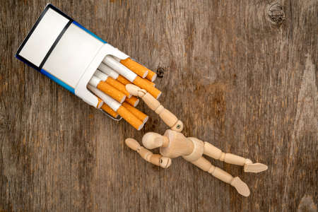 Wooden dummy takes a cigarette. Bad habit concept.の写真素材