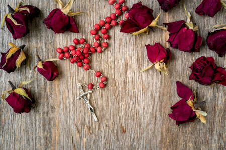 Faith and spirituality concept. Rosary and dry rose buds on the wooden backgroundの写真素材