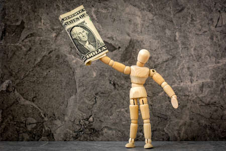 Wooden mannequin holding one dollar bill. Monetary concept.の写真素材
