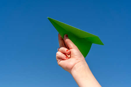 Paper plane in child hand on clear blue skyの写真素材