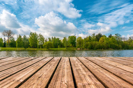 Idyllic view of the wooden pier in the lake with forest scenery background.