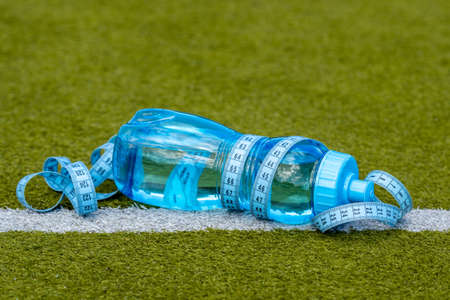 Plastic bottle of water with measure tape on green artificial grass at football fieldの写真素材