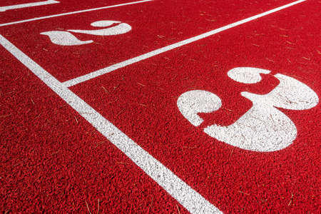 Numbers on start point of running track background. Red running track in stadium.の写真素材