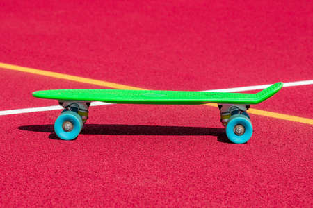 Green penny skateboard on the sports ground, summer outdoors