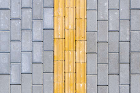Bright yellow tactile paving for the visually impaired on the sidewalk.の写真素材