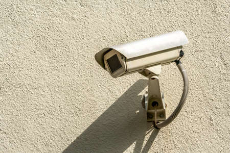 CCTV Camera on grey concrete wall with copy space. Security against crime & surveillance, mounted on house exterior wall.Video Camera Security Systemの写真素材