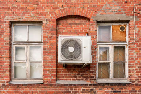 Outdoor air conditioning unit on the facade of a old brick house