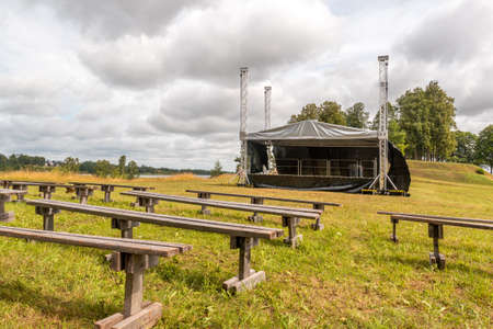 Empty rows of  wooden benches with the stage in the open airの写真素材