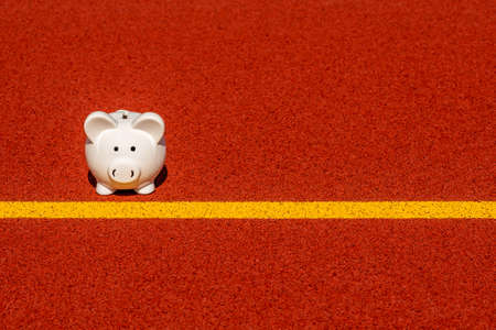 Piggy bank on the yellow starting line in the stadium. Copy space.の写真素材