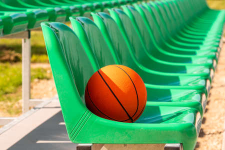 Line of stadium chairs with an orange basketballの写真素材