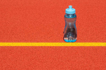Sports water bottle stands on a run track start lineの写真素材