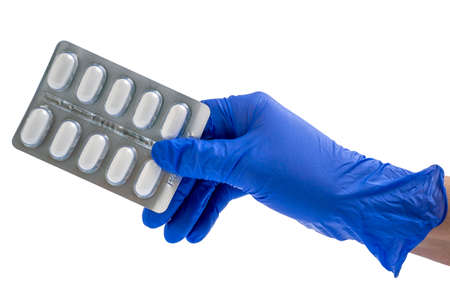 Doctor or scientist hand in blue nitrile glove holds a blister with pills.  Healthcare concept.