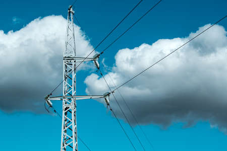 Metal electricity pole against cloudy sky background. High voltage electricity pylon.