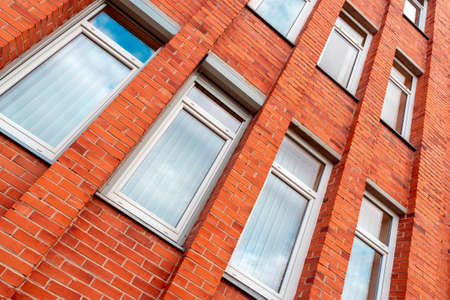 Red brick building wall with clouds reflections in windows