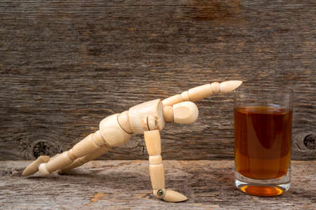 Alcohol addiction - wooden man reaching a glass of whiskeyの写真素材