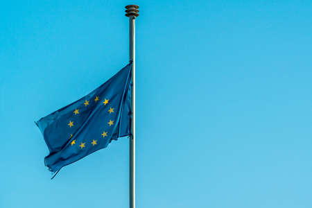 Ragged European Union flag on pole in the airの写真素材
