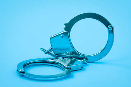 Handcuffs lying on the blue background. Blue filtered image.の写真素材