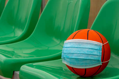 Basketball ball on the chairs of empty stadium with medical face mask. Corona virus protection.の写真素材