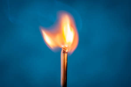 Ignition of a match, with smoke on blue background. A beauty of burning match. Fire styling.