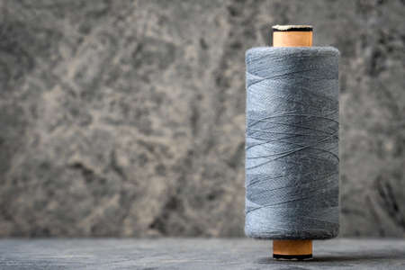 Spool of grey thread on a stone background. Copy space.