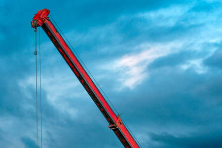 Boom of mobile crane with cloudy sky background. Red boom of crane.の写真素材